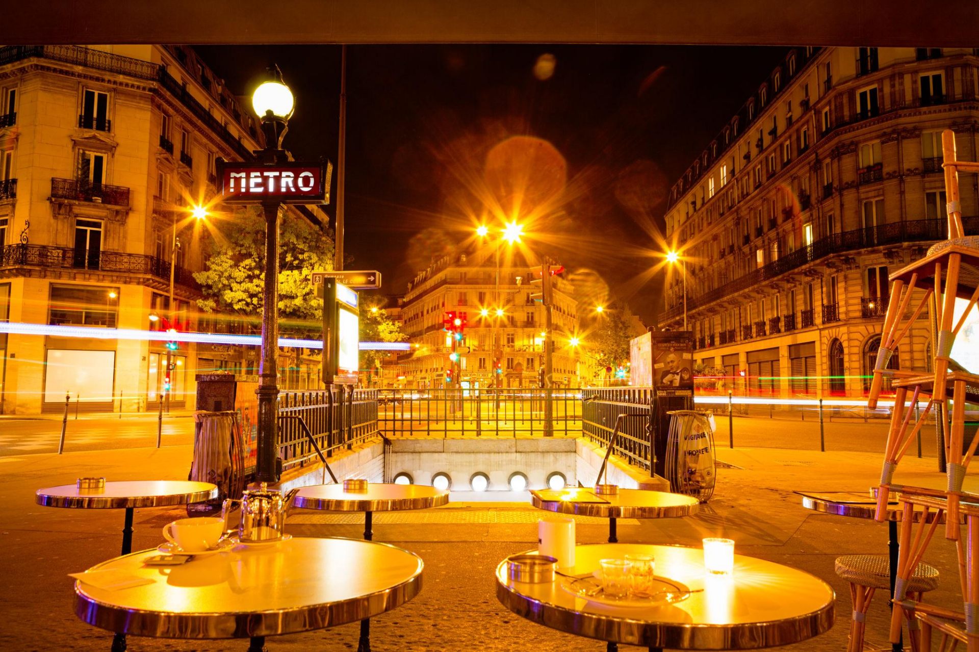 Parisian café terrace by a Metro entrance at night